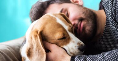 man cuddling dog looking happy