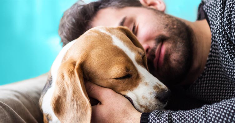 man cuddling dog looking happy