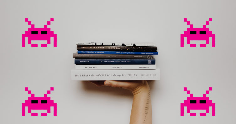 person holding books with space invaders