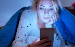 Woman in bed looking at phone