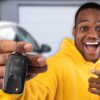 man holding car key in front of car in driveway