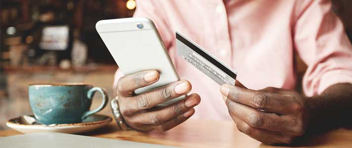 Man in coffee shop with credit card and phone