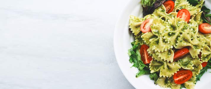 pesto pasta with lettuce and tomato on a plate