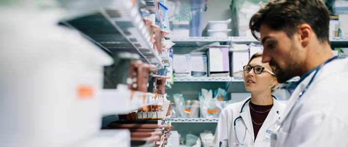 pharmacists near a rack filled with medicine