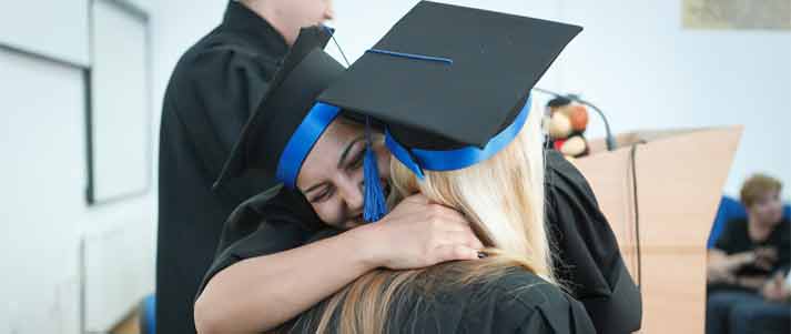 two graduates hugging