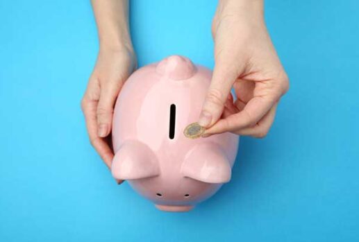 Hand putting pound coin into piggy bank