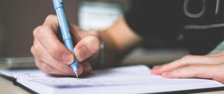 person writing in a notepad with pen